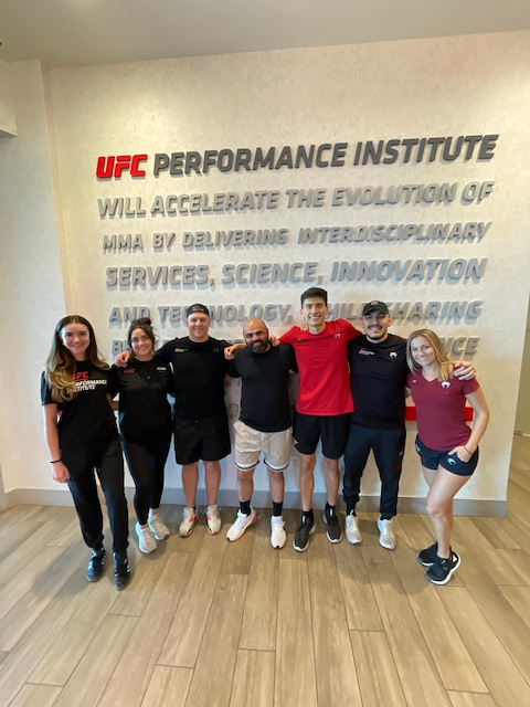 Luigi Meli (Montreal nutritionist) and his team posing in front of a UFC Performance Institute sign.
