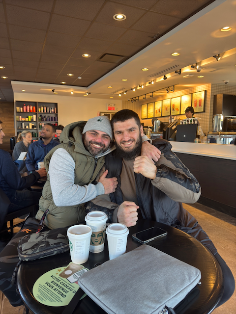 Luigi Meli (nutritionist based in Montreal) hugging his client at a table with Starbucks cups in a coffee shop.